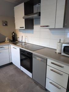 a kitchen with white cabinets and a sink and a stove at Pfoten & Komfort Barrierefrei in Butjadingen