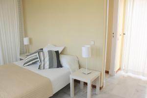 ein Schlafzimmer mit einem Bett und einem Tisch mit einer Lampe in der Unterkunft Apartamentos Puerto Sherry in El Puerto de Santa María