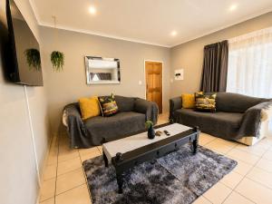 a living room with two couches and a tv at Zhantique Guest House 2- Unit 6 in Boksburg