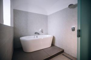 a white tub in a bathroom with white tiles at 4 Rooms in Maribor