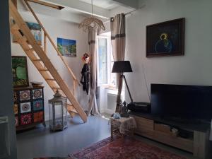 a living room with a flat screen tv and stairs at Les volets bleus in Prémian