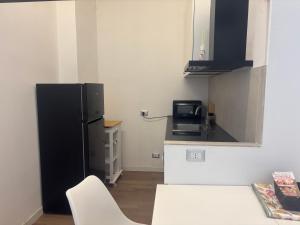 a kitchen with a black refrigerator and a white chair at Milano side house apartment in Sesto San Giovanni