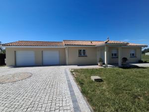 a house with two garage doors in a yard at Gîte du Pont Neuf & SPA in Eyrans-de Soudiac
