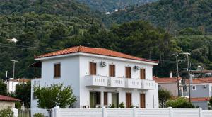 a white house with a white fence in front of a mountain at Matina's house in Samos