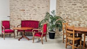 a dining room with red chairs and a table and a plant at La Valdonnière in Esnoms-au-Val