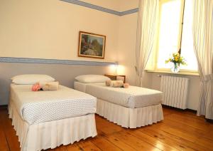 two beds in a room with wooden floors and a window at Teddy Bear trilocale, family, centro Biella in Biella