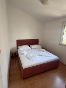 a bedroom with a bed with white sheets and a window at Apartmani Maleš in Rogoznica