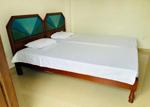 a bed with white sheets and pillows in a room at Cloud Nine in Diyatalawa