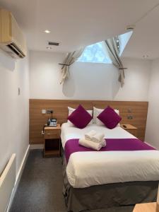 a bedroom with a bed with purple pillows and a window at Elysee Hyde Park in London +103 photos