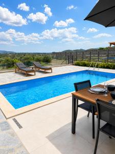 a swimming pool with a table and chairs and an umbrella at Elysian View Lefkakia in Nafplio
