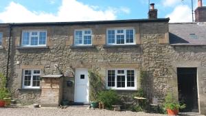 an old stone house with white doors and windows at The Stables, 2 Plough Square in Glanton