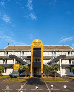 a large building with a large yellow sign in front of it at Première Classe Tarbes - Bastillac in Tarbes