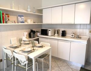 a kitchen with a white table and chairs in a kitchen at Teddy Bear trilocale, family, centro Biella in Biella