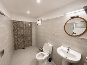 a bathroom with a toilet and a sink and a mirror at Happy Waves Morocco - Surf Hostel Tamraght in Tamraght Ou Fella +26 photos