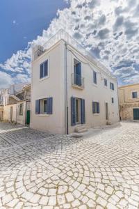 a large white building on a cobblestone street at la perla sul mare in Sampieri