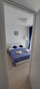 a bedroom with a blue bed with two towels on it at Apartamentai “Viola” Juodkranteje in Juodkrantė
