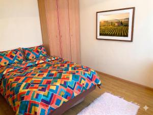 a bedroom with a colorful bed and a painting on the wall at Furedi Apartman in Balatonfüred +9 photos