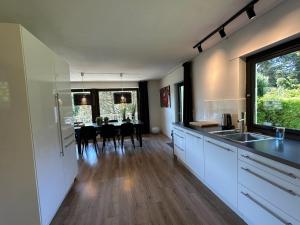 a kitchen with white cabinets and a table with chairs at Villa Im Bongert - Tor zum Nationalpark Eifel in Hellenthal