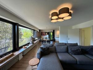 a living room with a blue couch and large windows at Villa Im Bongert - Tor zum Nationalpark Eifel in Hellenthal