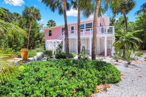 a pink house with palm trees in front of it at Pink Shell Sanibel in Sanibel