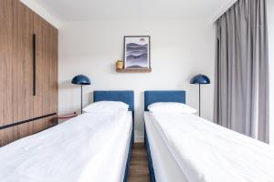 two beds in a room with white walls at Noli Gdansk Wrzeszcz in Gdańsk