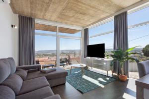 a living room with a couch and a tv and windows at Colina do Sol 1 in Amoreira