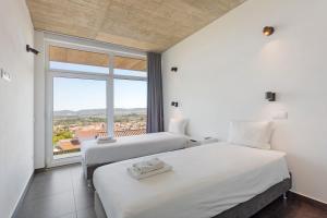 two beds in a room with a large window at Colina do Sol 1 in Amoreira +23 photos
