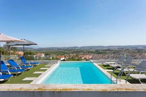 a swimming pool with chairs and an umbrella at Colina do Sol 1 in Amoreira