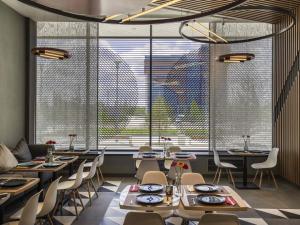 a restaurant with tables and chairs and large windows at Ibis Aktobe in Aktobe