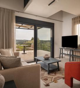 a living room with a couch and a tv at Enos Retreat Villas in Agios Nikolaos