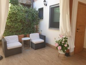 a patio with two chairs and a window and a plant at IL GIARDINETTO di Dilyana in Monterosi