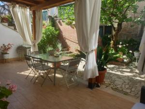 a patio with a table and chairs and curtains at IL GIARDINETTO di Dilyana in Monterosi