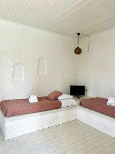 a bedroom with two beds and a tv on the wall at Cascade Holiday Resort in Poros