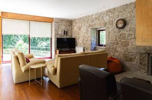 a living room with couches and a stone wall at Holly Country House in Paredes de Coura