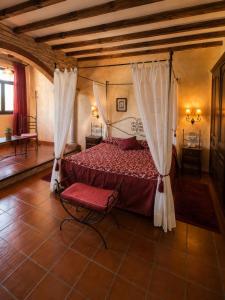 ein Schlafzimmer mit einem Bett mit Vorhängen und einem Stuhl in der Unterkunft Hotel Real Castillo in La Guardia