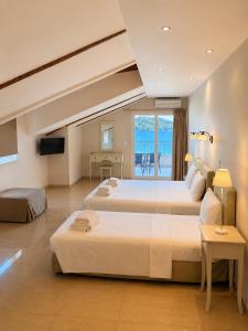 a hotel room with two beds and a television at Akrogiali Studios - Nidri, Lefkada in Nydri