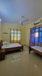 a bedroom with two beds in a room with windows at WamkHouse in Jambiani