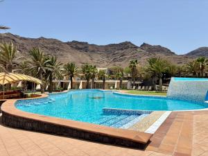 a swimming pool with palm trees and mountains in the background at Lam Hotel Foya Branca in São Pedro
