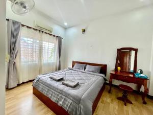 a bedroom with a bed and a table and a mirror at Pkar Thmor Siem Reap Guest House in Phumĭ Réach Born (2)