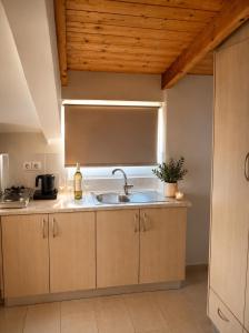 a kitchen with a sink and a wooden ceiling at Akrogiali Studios - Nidri, Lefkada in Nydri