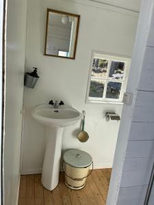 a white bathroom with a sink and a mirror at Svens Stuga in Burträsk +28 photos