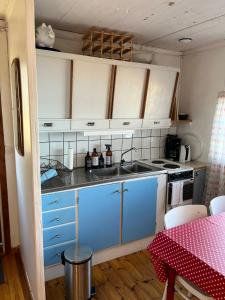a small kitchen with blue cabinets and a table with a red table cloth at Svens Stuga in Burträsk