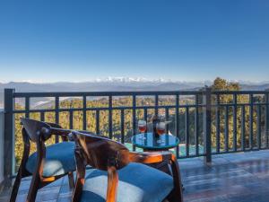 a table with two glasses of wine on a balcony at Dharohar Retreat, Mukteshwar in Mukteshwar