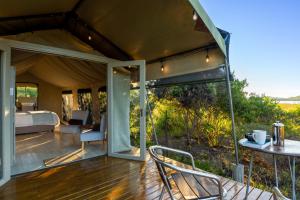 a tent bedroom with a bed and a table and chairs at Reflections Eco-Reserve in Wilderness