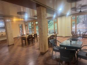 a dining room with tables and chairs and windows at The Zoland in Jibhi