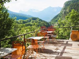 a wooden deck with tables and chairs and mountains at AO HOUSE - Chalet PAN BENA in Les Houches