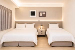 two beds in a bedroom with white sheets at T and C 民宿 in Wujie