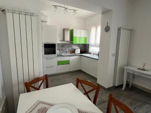a kitchen with white cabinets and a table with chairs at Casa Fellini - Giardino e parcheggio gratuito in Venturina Terme +6 photos