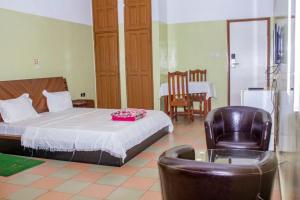 a bedroom with a bed and a chair and a table at NIF-UR Hotel Bohicon in Bohicon +16 photos