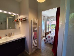 a bathroom with a sink and a mirror and a bedroom at Le petit nid dans les bois in Castres-Gironde +19 photos